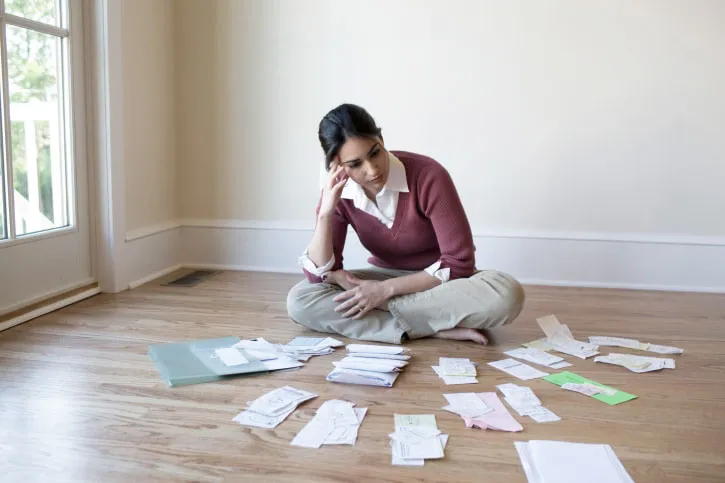 Woman looking at bills and receipts on floor