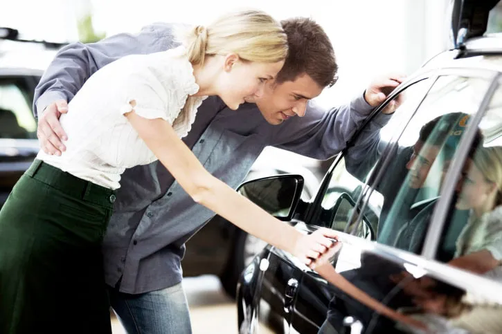 A young couple admiring a new car