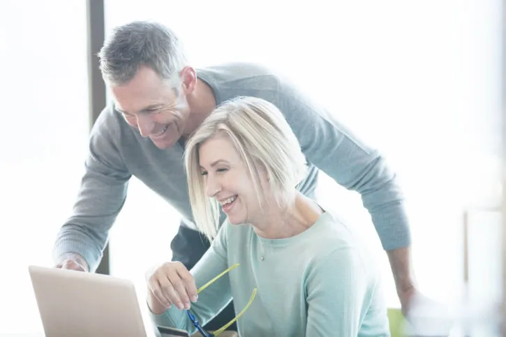 male and female couple smiling over laptop screen