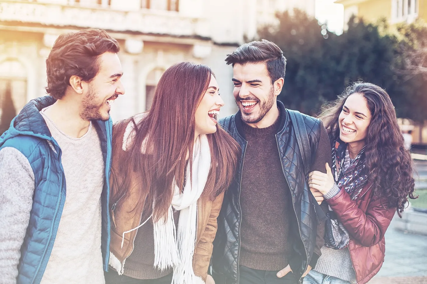 A group of college students smiling and laughing together while walking on campus.