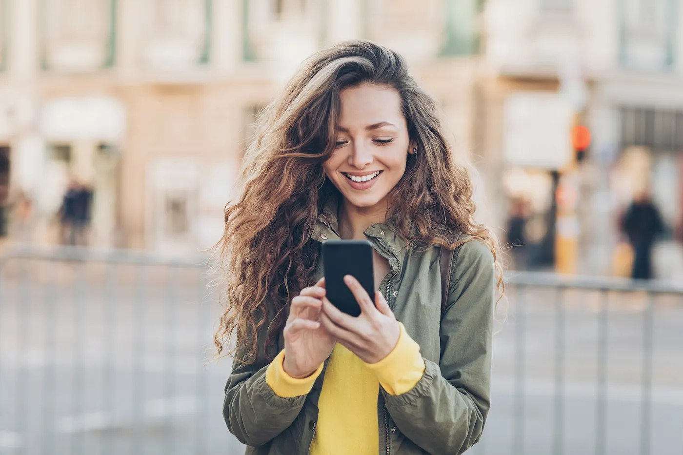 Young woman investing on her smart phone outdoors in the city