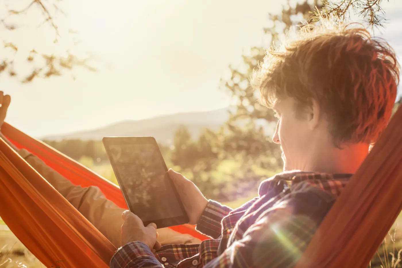 Side view of man using digital tablet in hammock