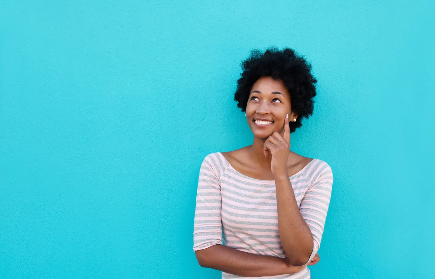 woman in stripped shirt smiling against blue wall