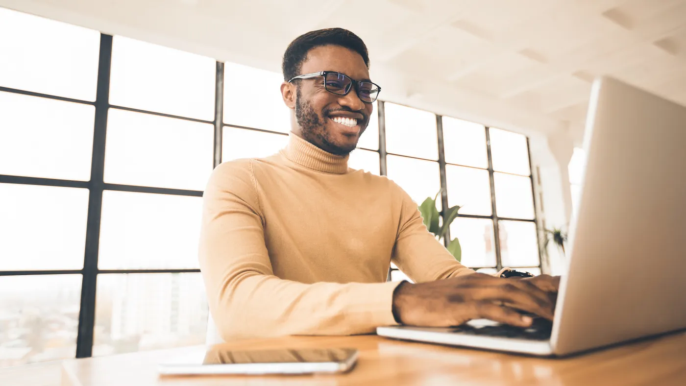 Happy man checking his high-yield savings account on a laptop.