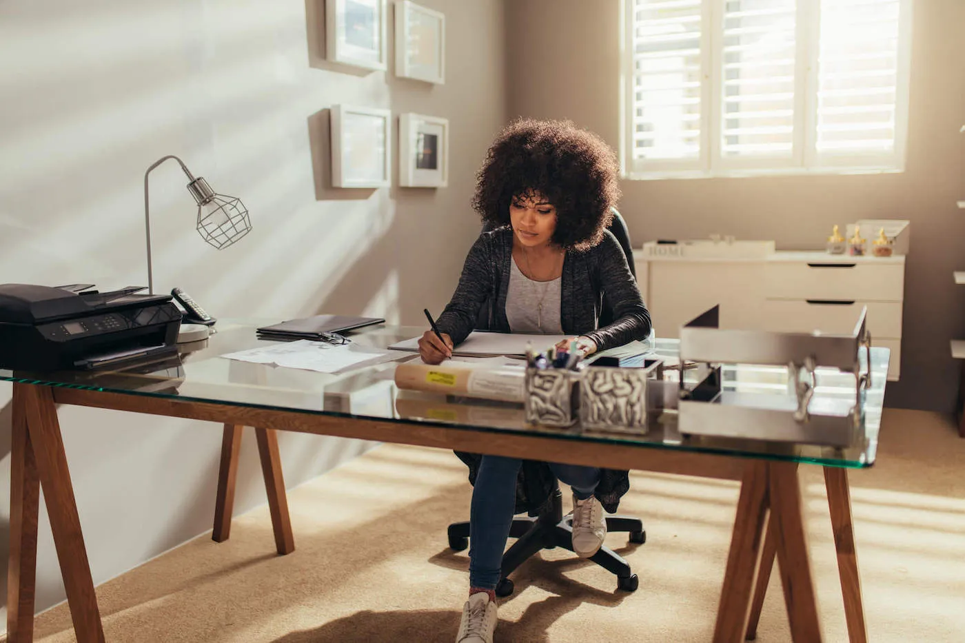 A woman is at home and writes on a piece of paper from her work desk.