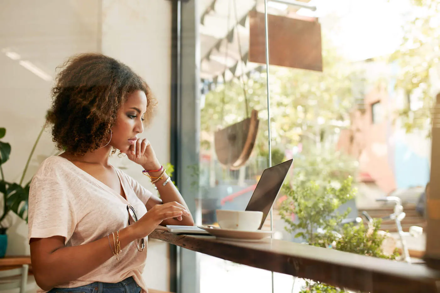 A young woman looks at her laptop computer inside a coffee shop.