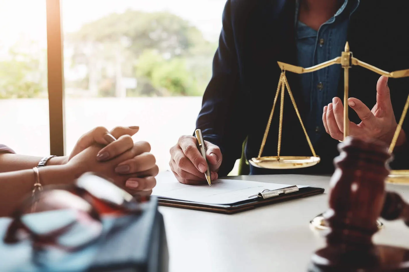 An attorney writes on a document while a client looks on across from them.