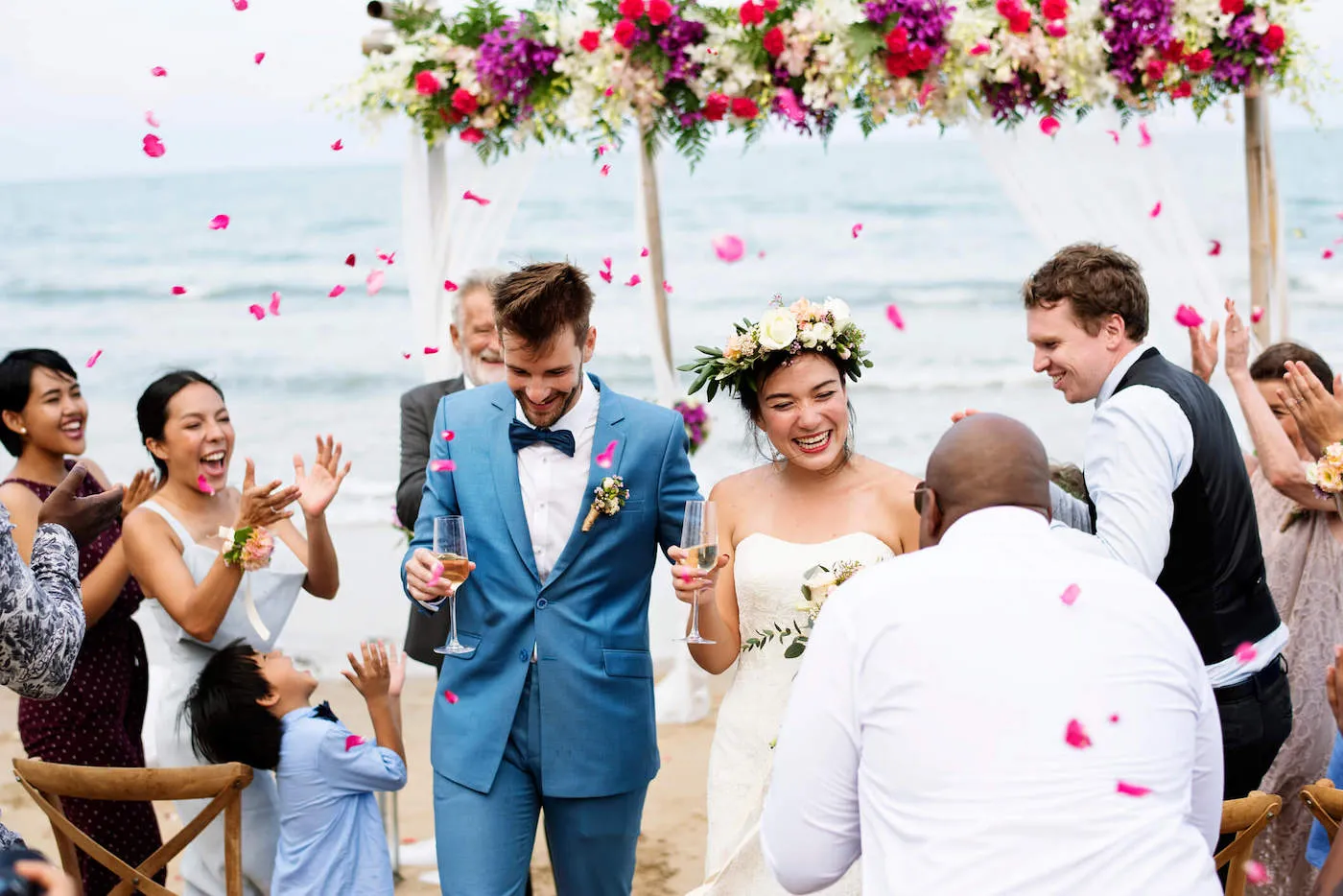 The bride and groom laugh while walking down the aisle after getting married at the beach.