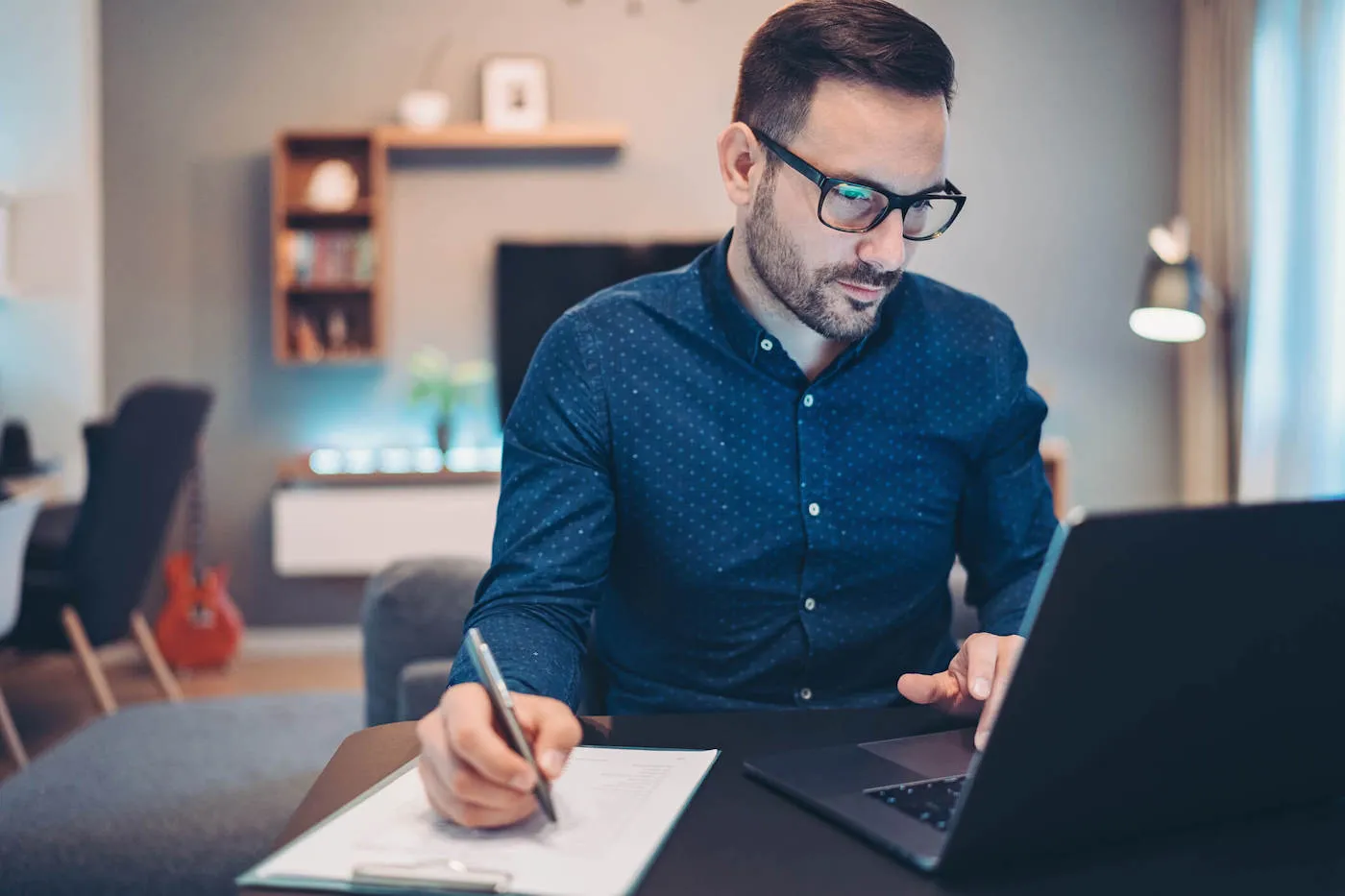 Businessman using laptop and doing paperwork at home.