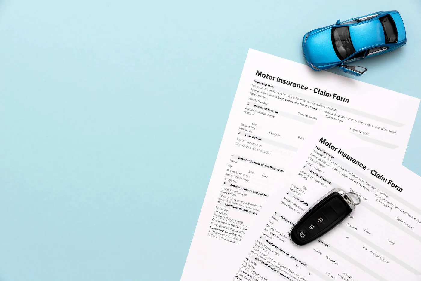 blue car miniature on top of blue tables with car insurance papers