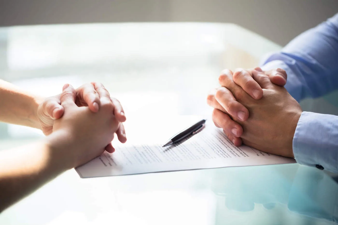 Close-up Of Two Businesspeople Hands With Document On Desk.