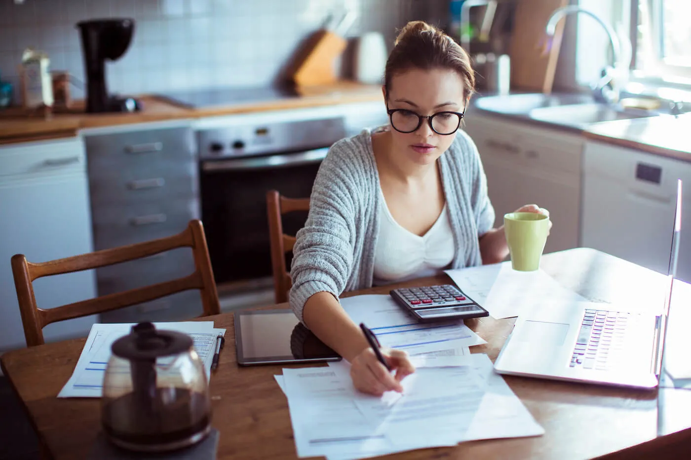 Close up of a young woman doing her bills in the kitchen.