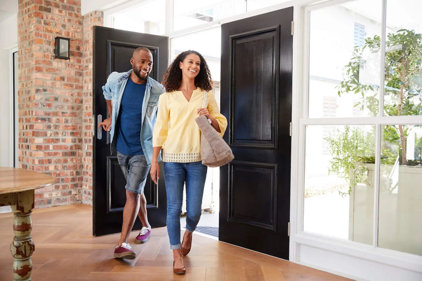 A couple walking inside of their home from the front door while smiling.