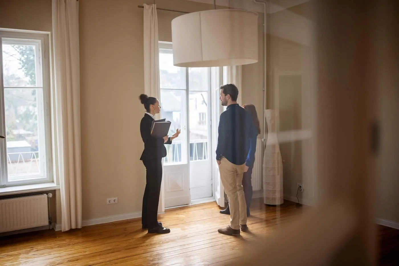 three people conversing in a shadowed house corridor