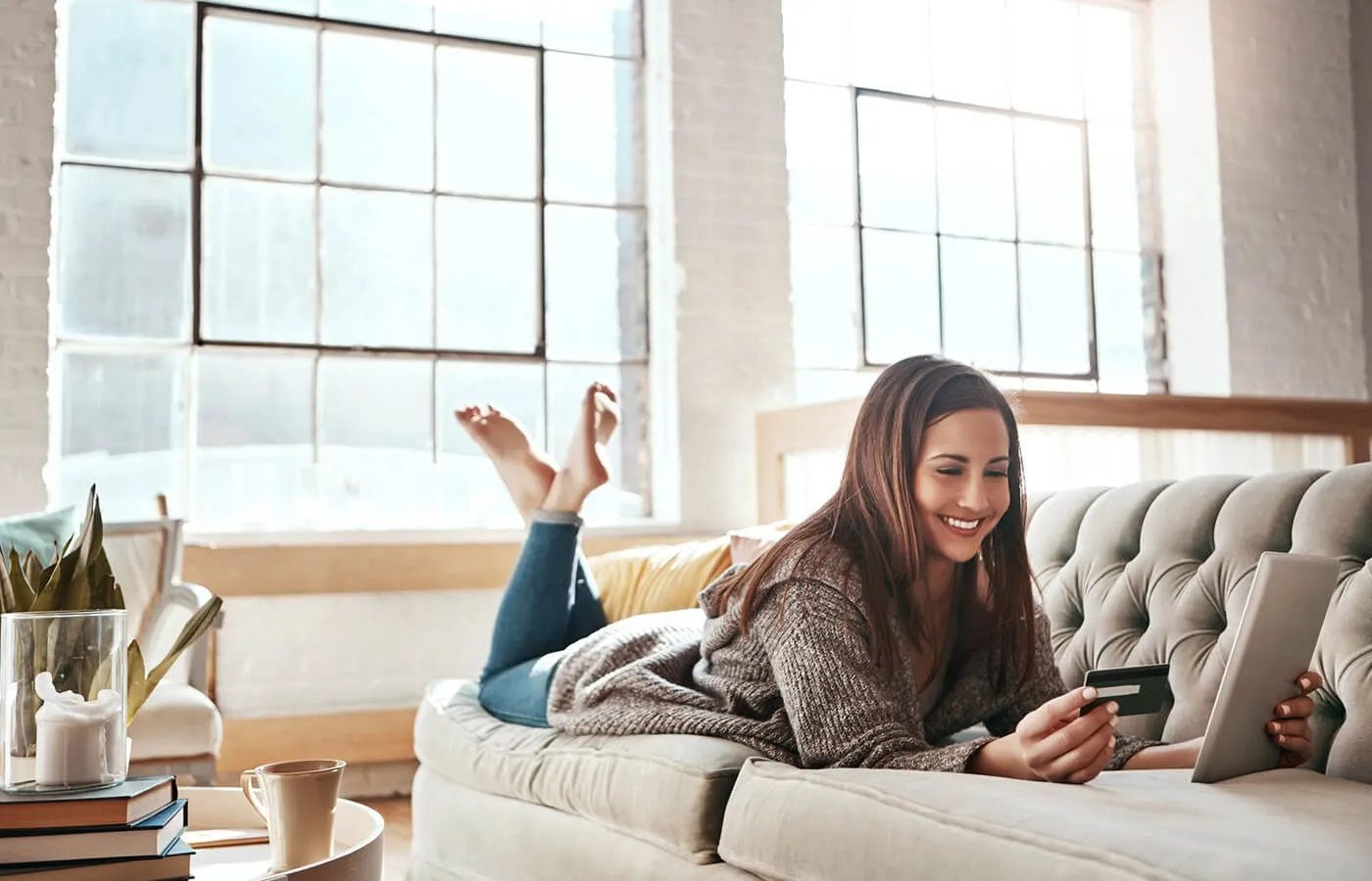 A woman laying on the couch and paying off debt.