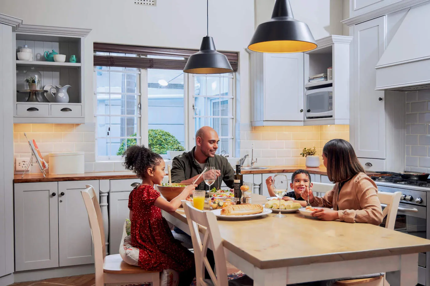 A family of four are eating at the dinner table together.