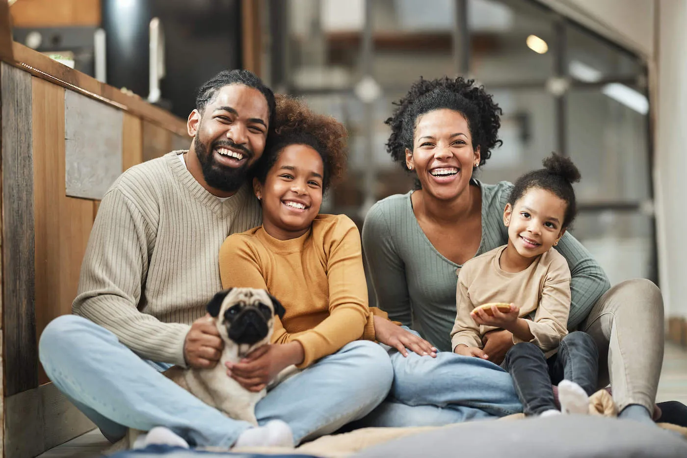 A family of four smile together with their dog at home.