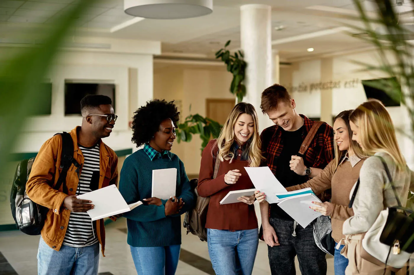 A group of college students smile as they hold their school supplies.