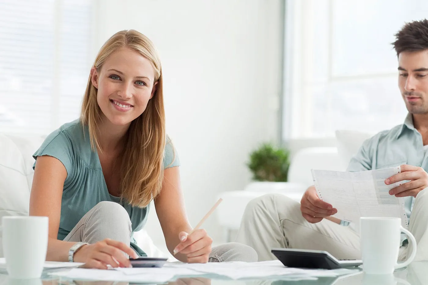 A woman smiles as she holds her credit card while the man next to her looks at a document.