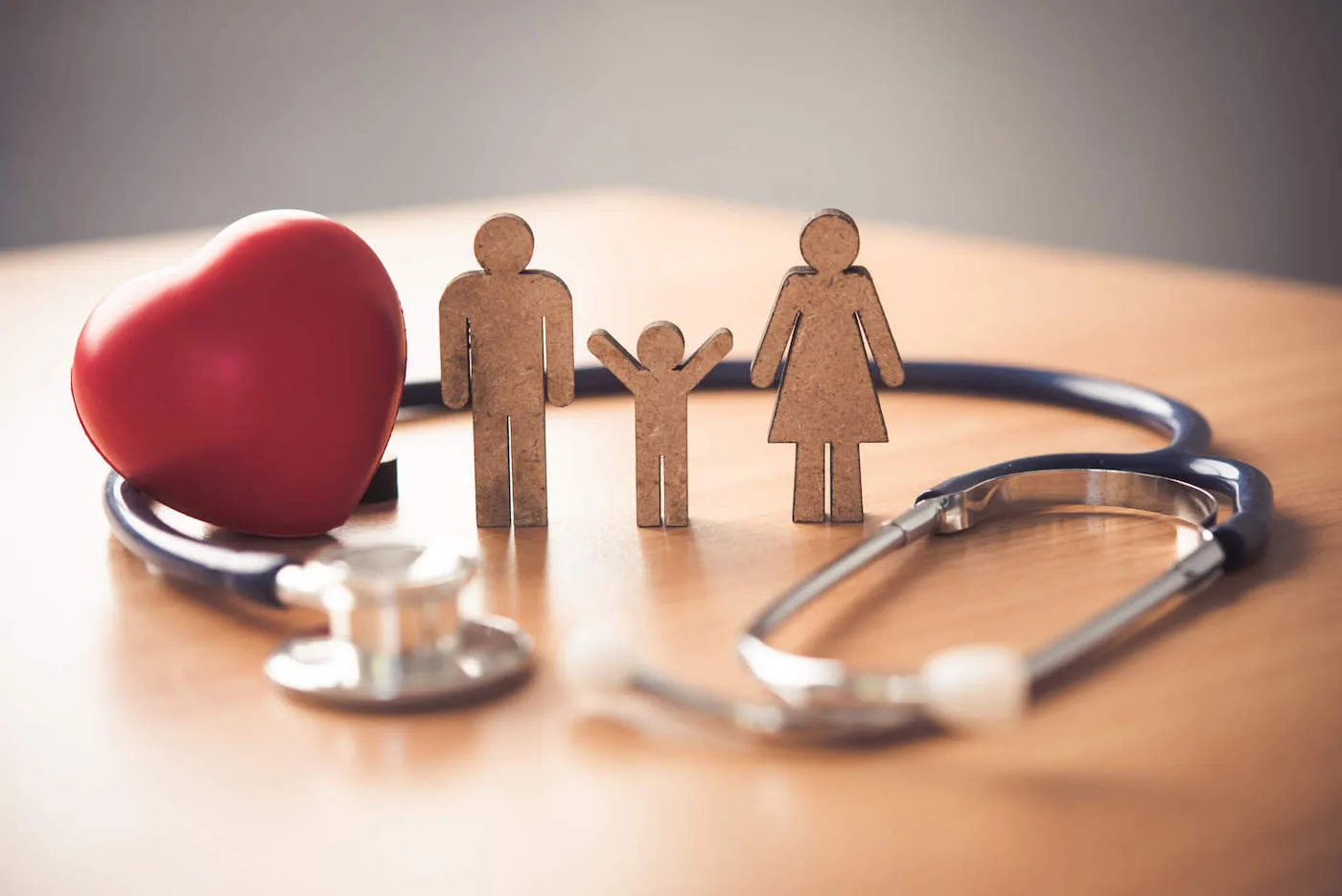 stethoscope on table surrounding miniature family of three figures