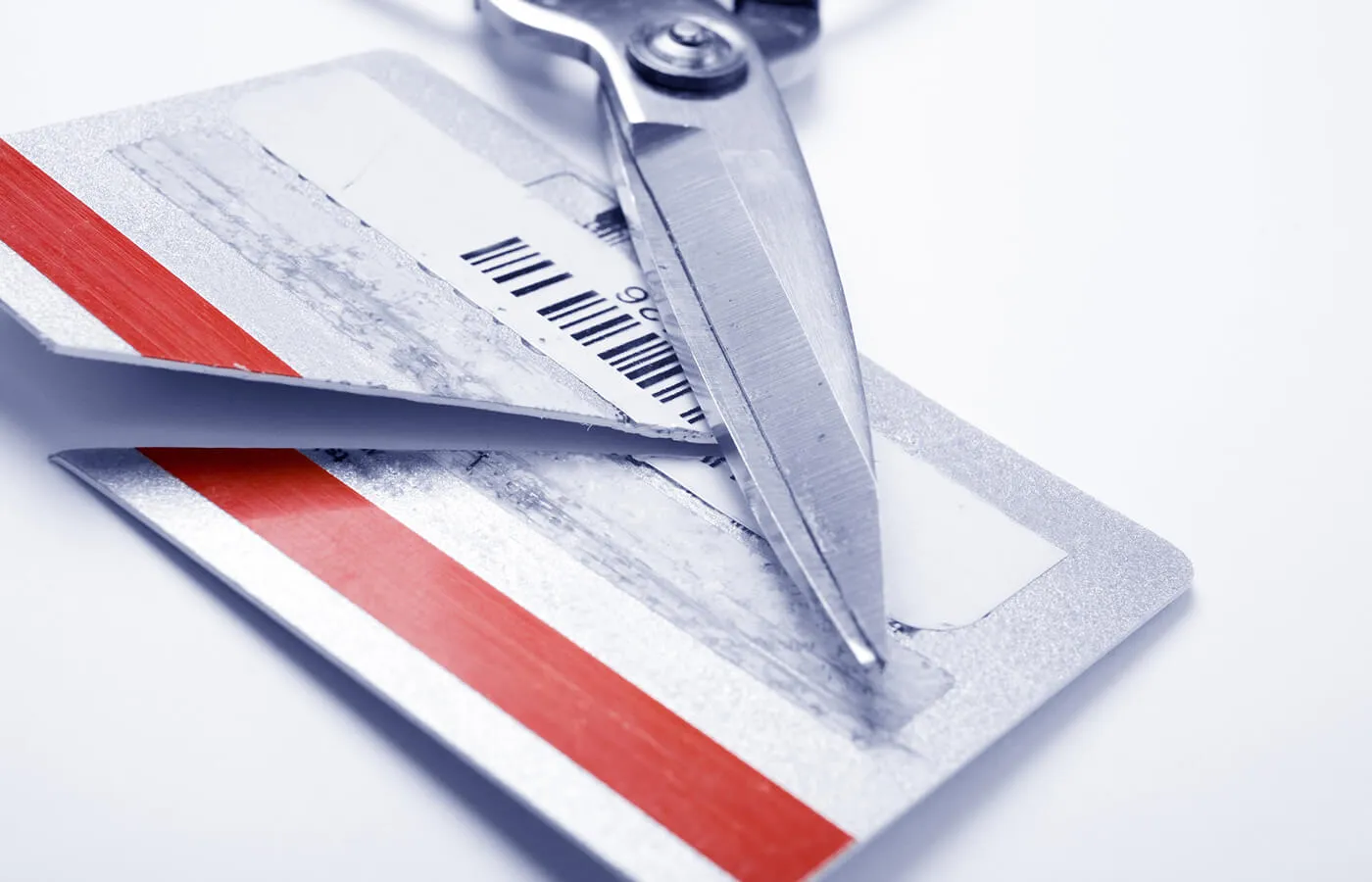 A pair of scissors resting on top of a credit card that's been cut diagonally down the center.