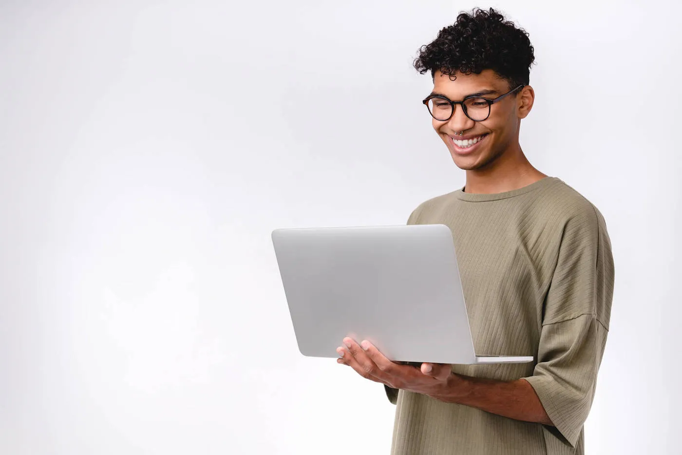 transgender individual in grey t-shirt holding laptop against light grey wall