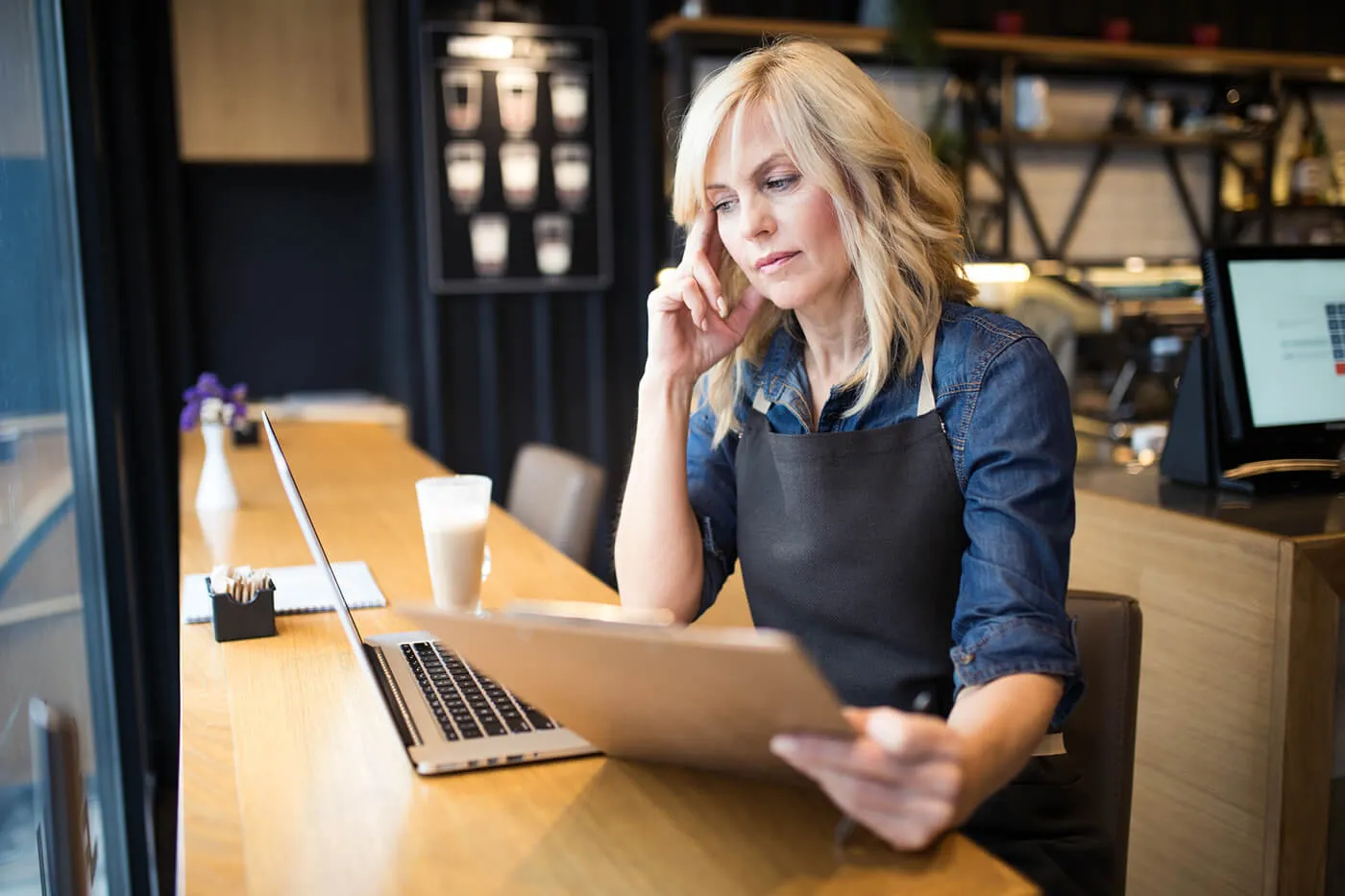 A cafe owner looking at bills at the serving counter.