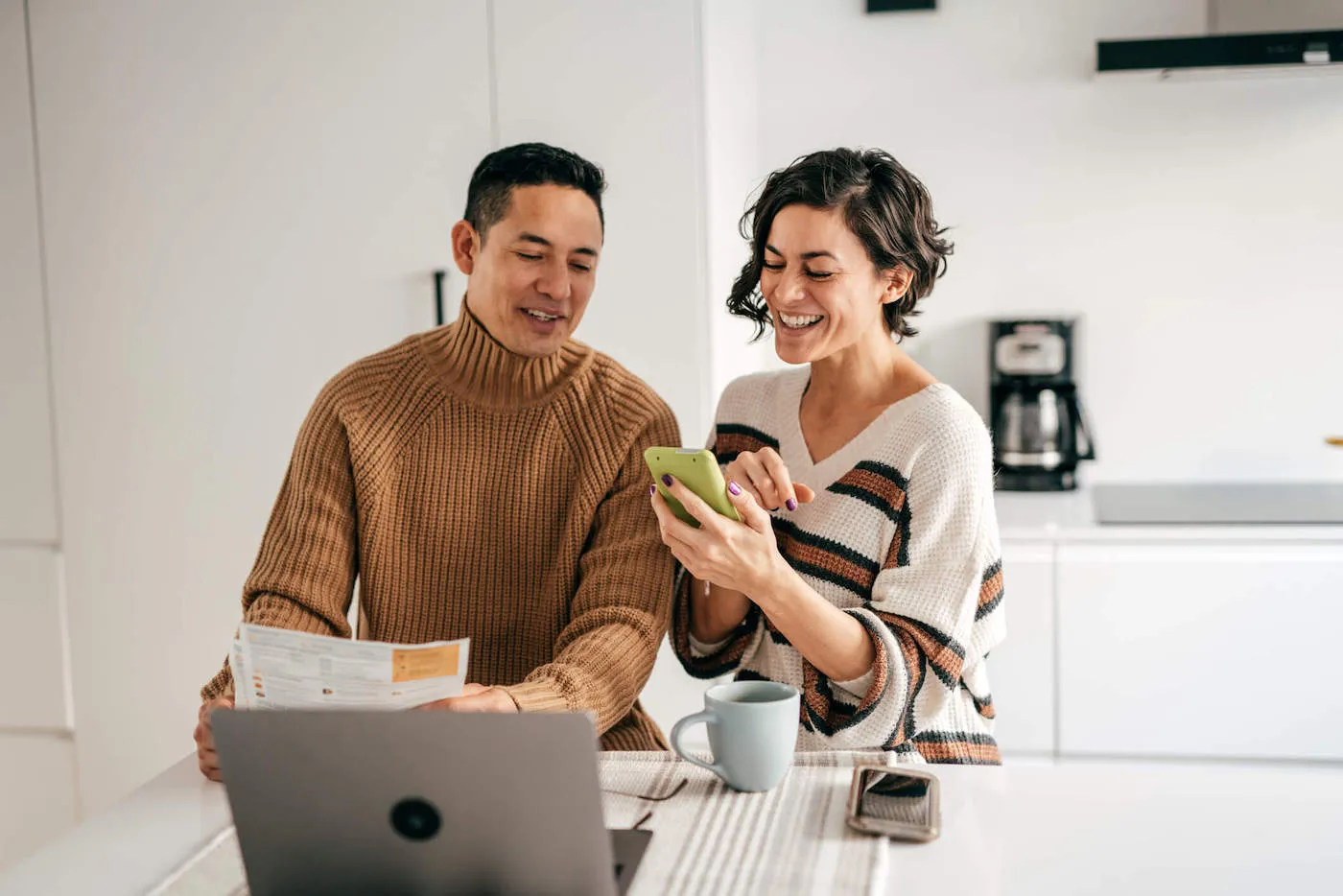 man and woman couple investing money seated at kitchen counter