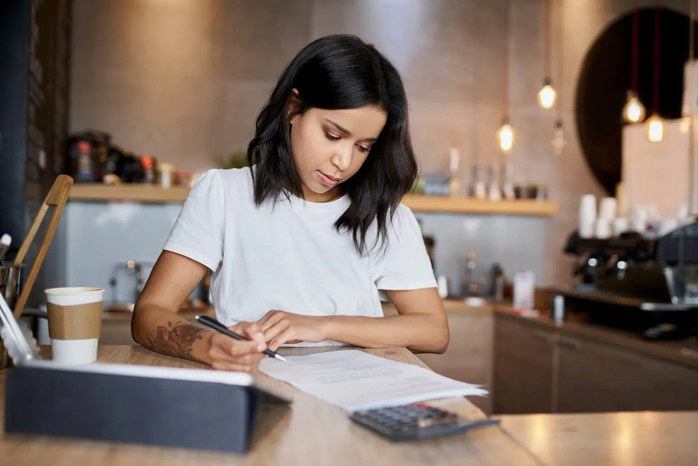 young woman in white t-shirt writing on paper