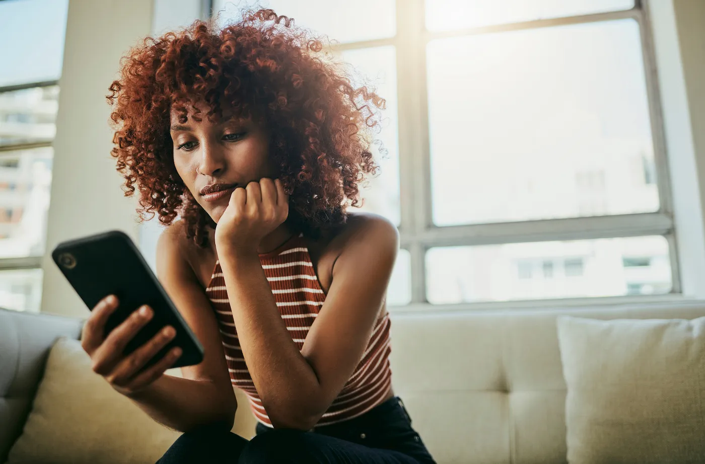 Woman checking email on her phone for news of a credit card application.