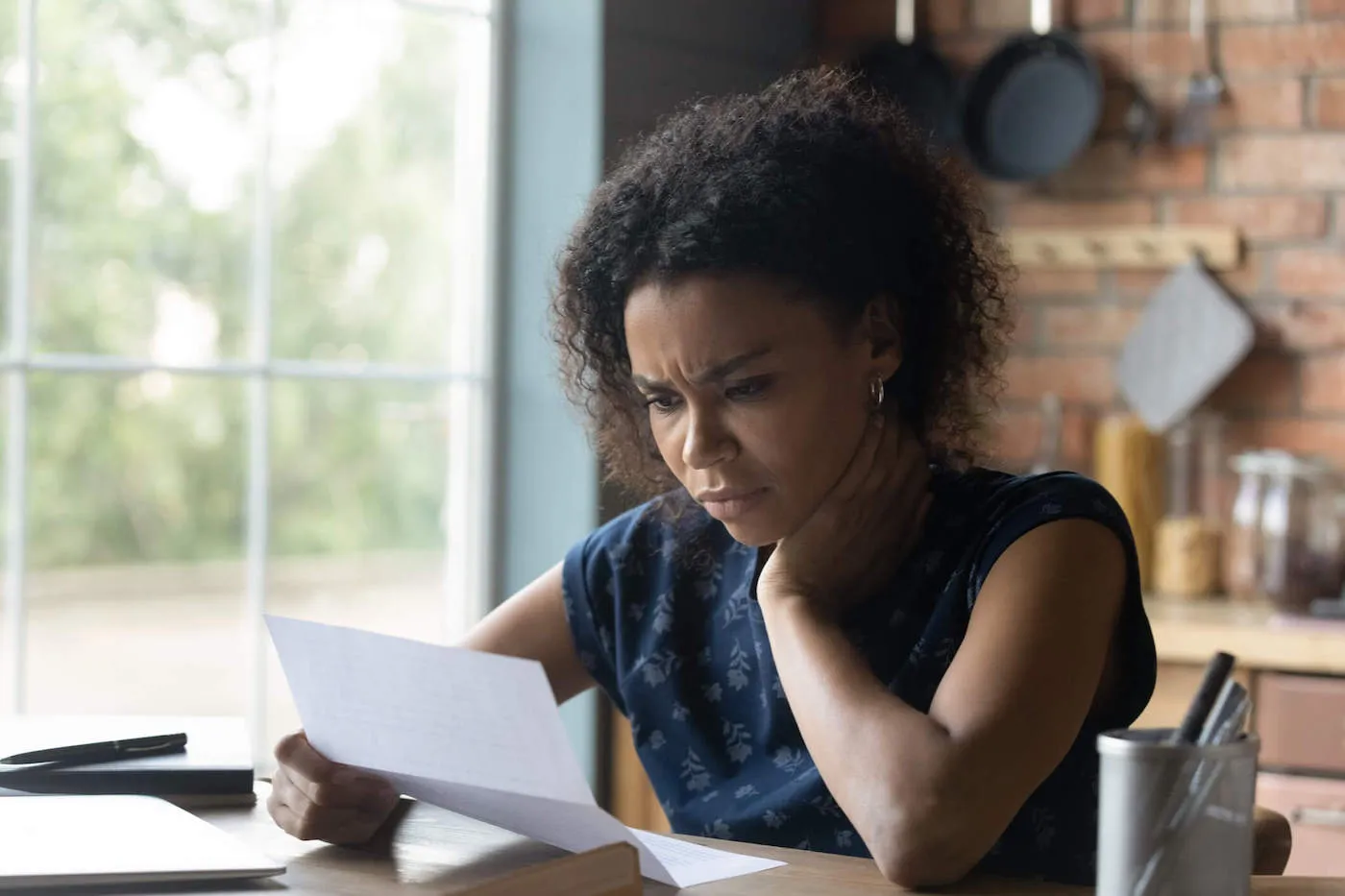 woman sitting by window looking at paper wondering if life insurance is taxable