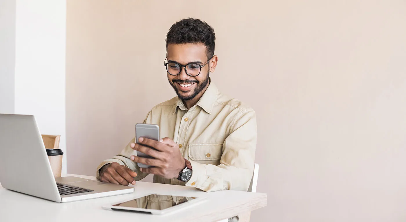 Men using laptop computer and texting on mobile phone.