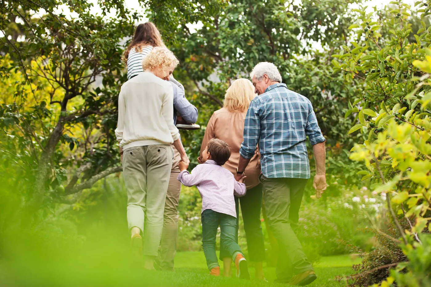 Multi-generation family walking in park.