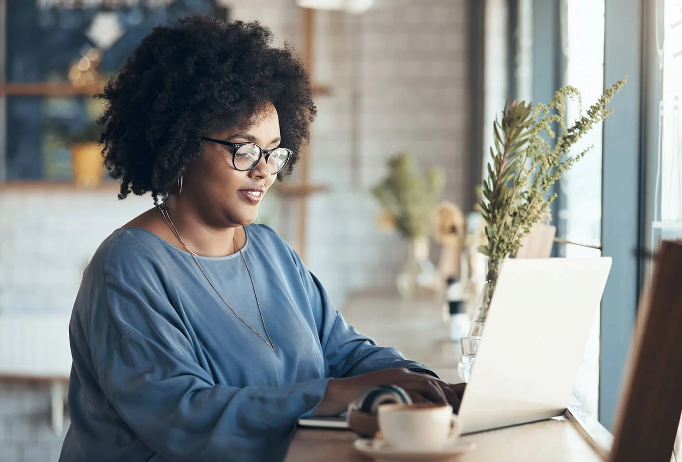 Shot of a young businesswoman sitting and working on her laptop in a coffee shop during the day