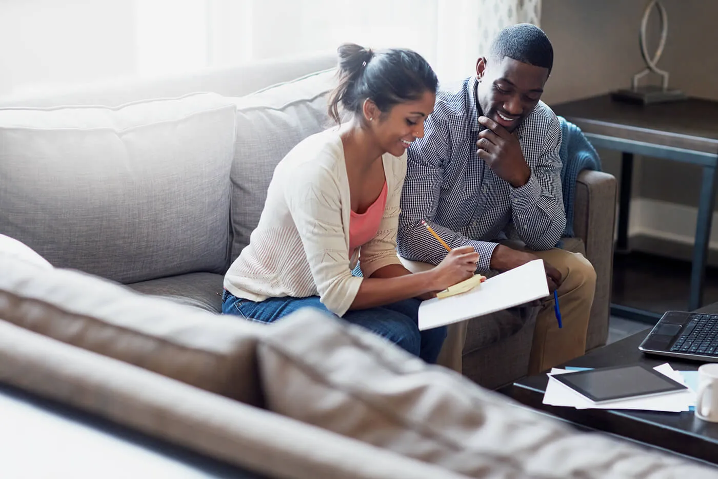 A man and a woman reviewing paperwork on the couch.