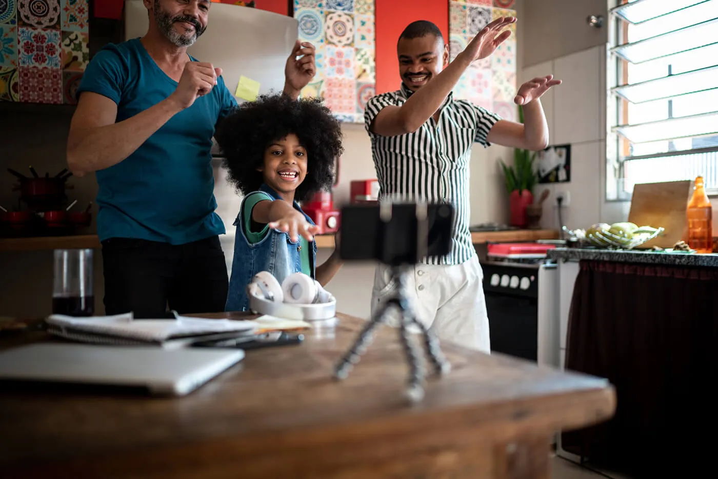 Family dancing at home, using smartphone on a tripod to film.