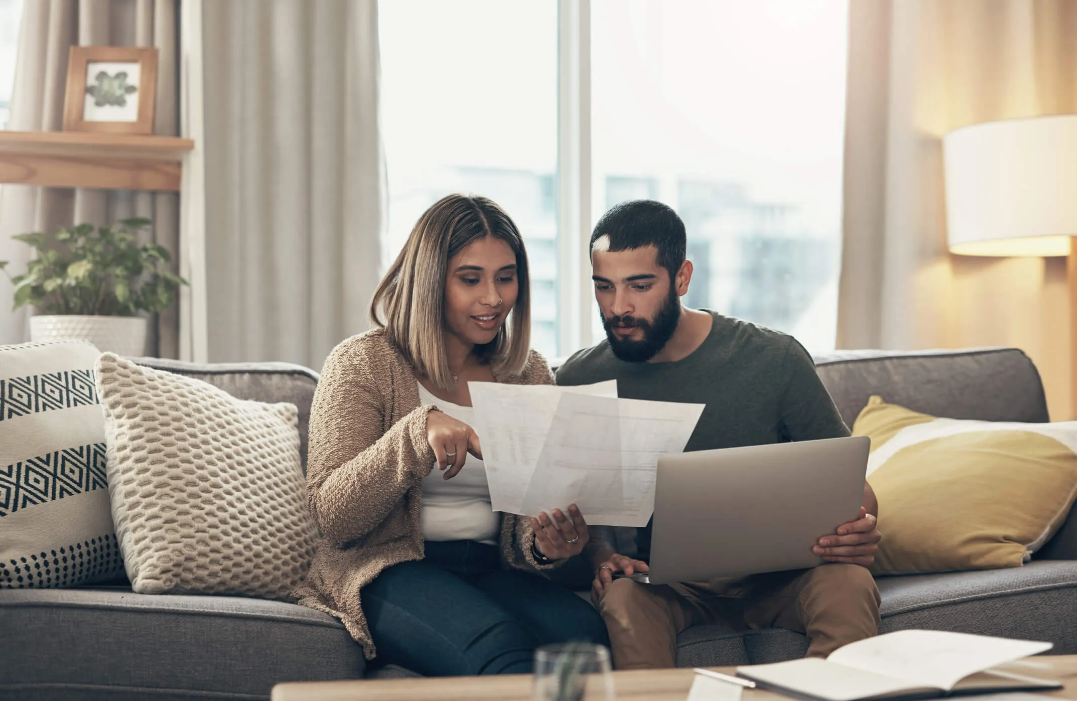 young man and woman couple seated on sofa looking over papers