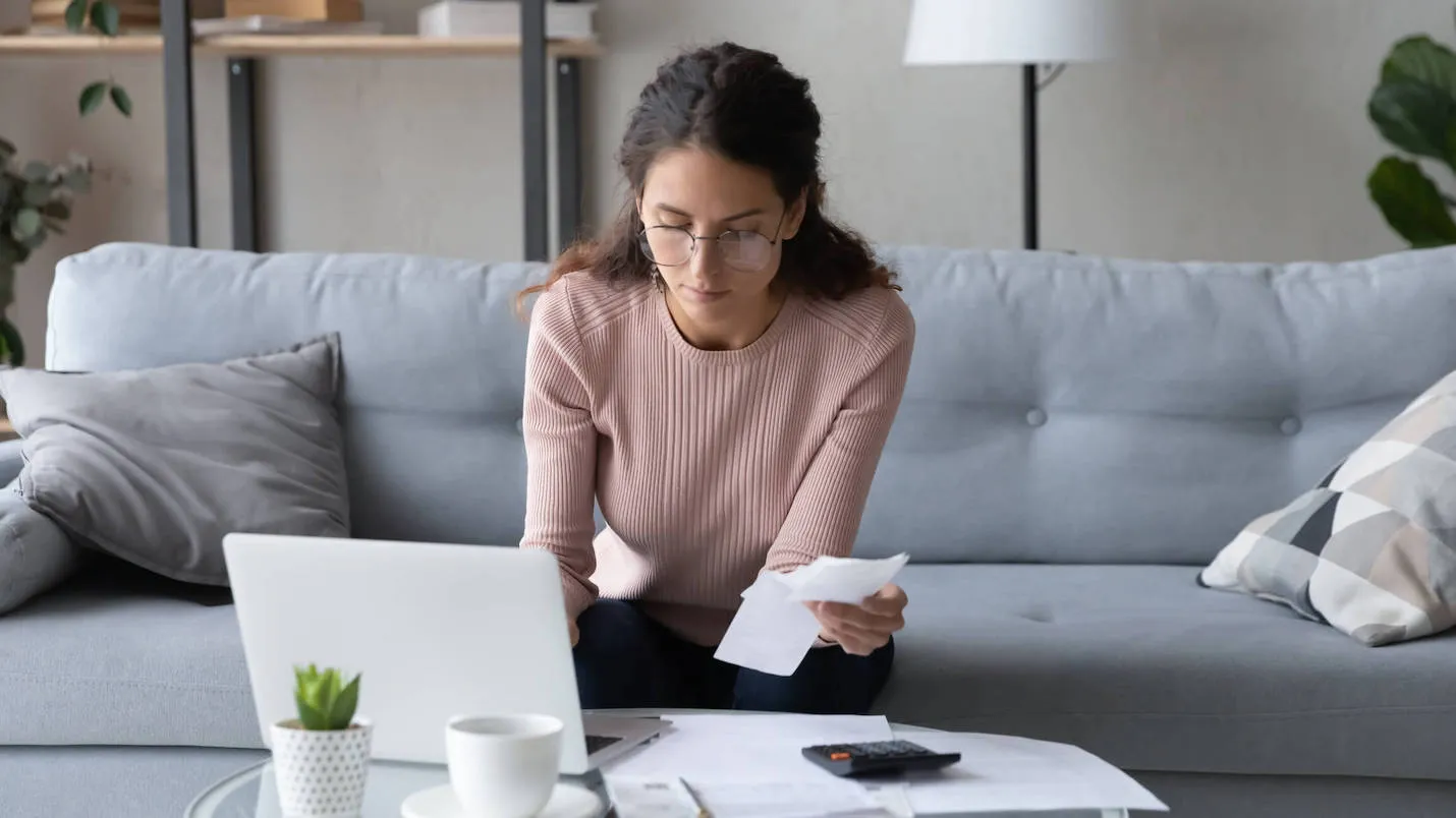 woman sitting on couch in living room looking over accrued interest