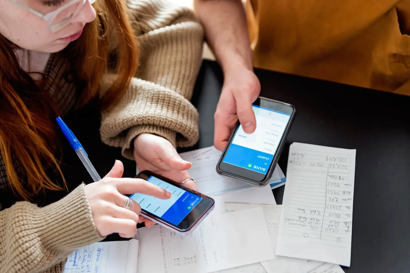 man and woman holding phones over spread papers