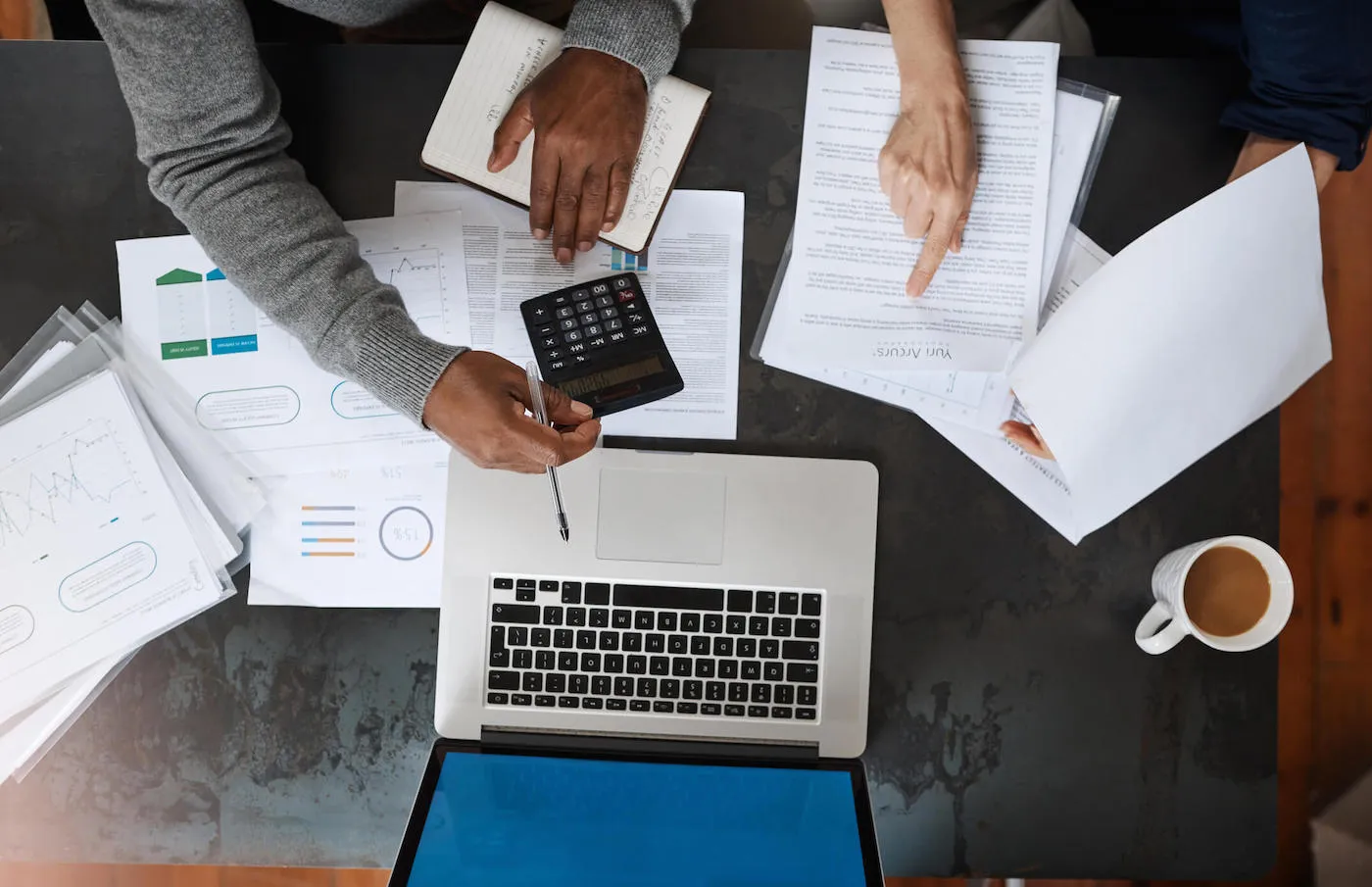 overtop shot of papers spread on a table next to open laptop