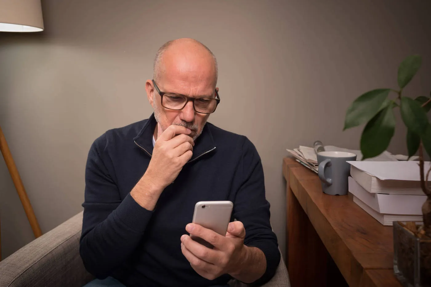 bold man in dark shirt looking worriedly at his phone