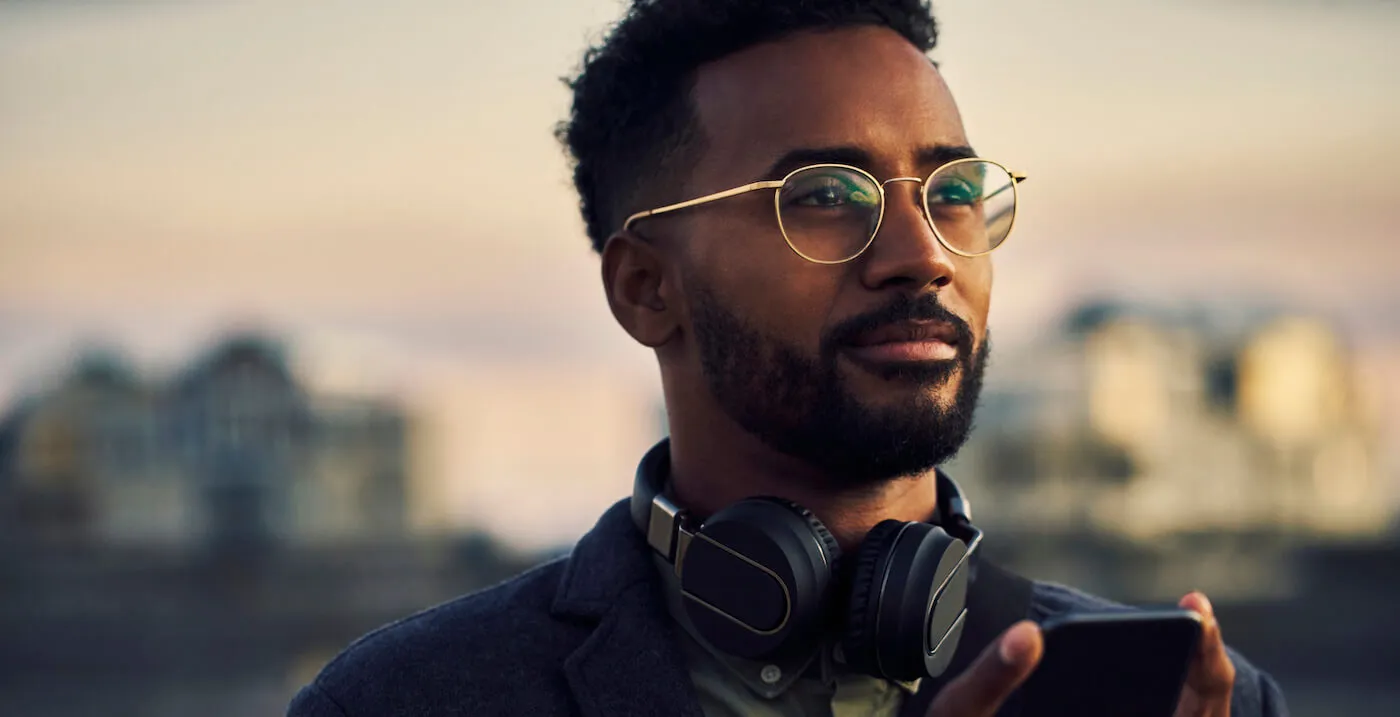 man in glasses with headphones around neck looking pensive