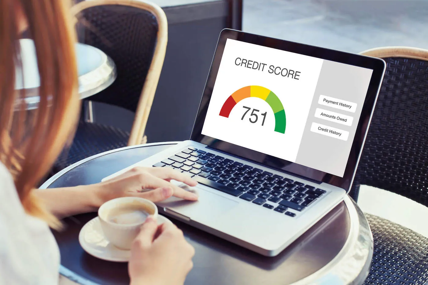 woman drinking coffee looking at credit score on laptop