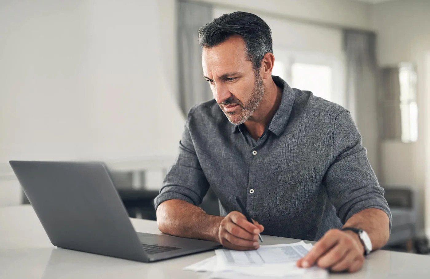 A man researching online using laptop while seated by counter.