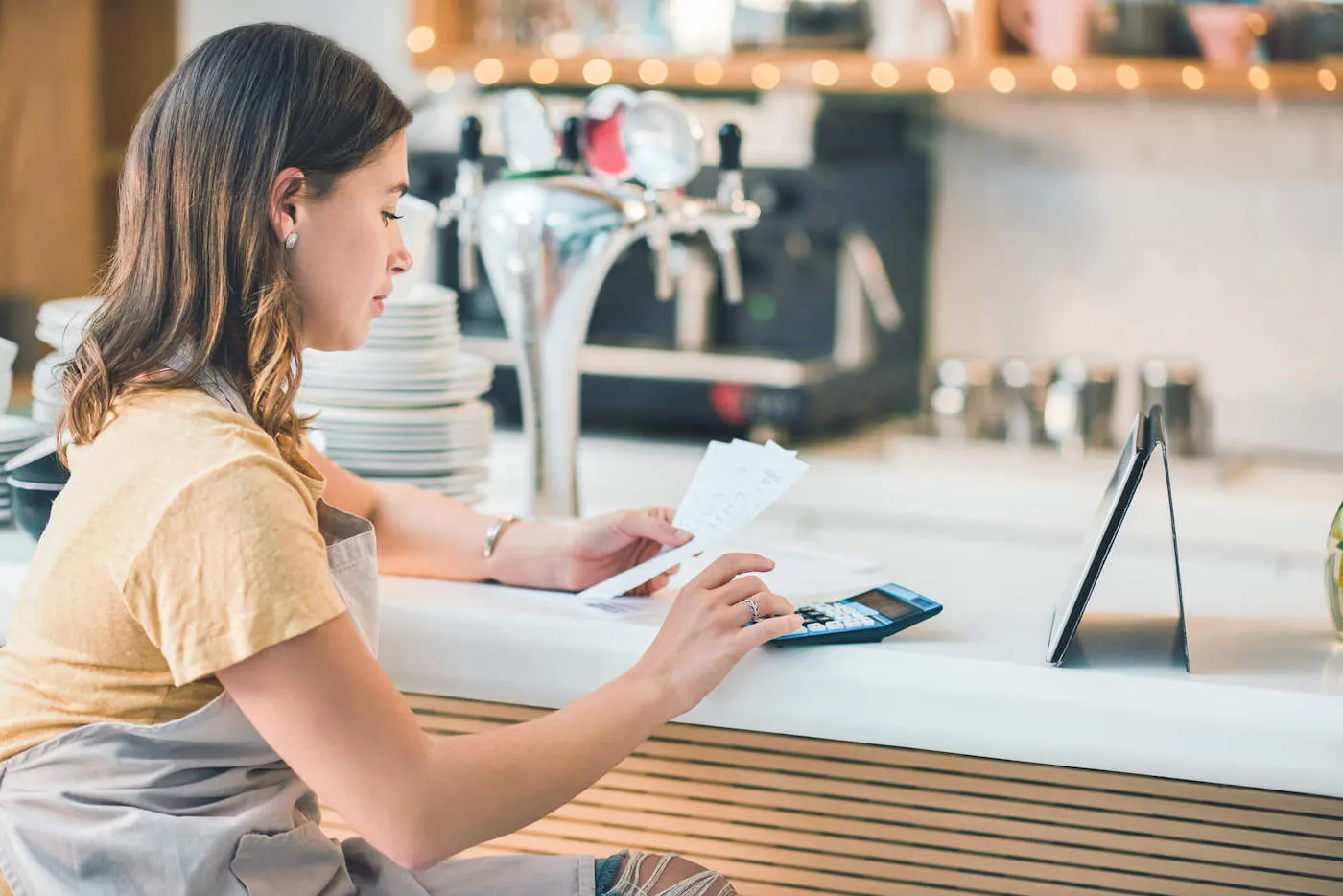 A woman typing on a calculator while looking at receipts.