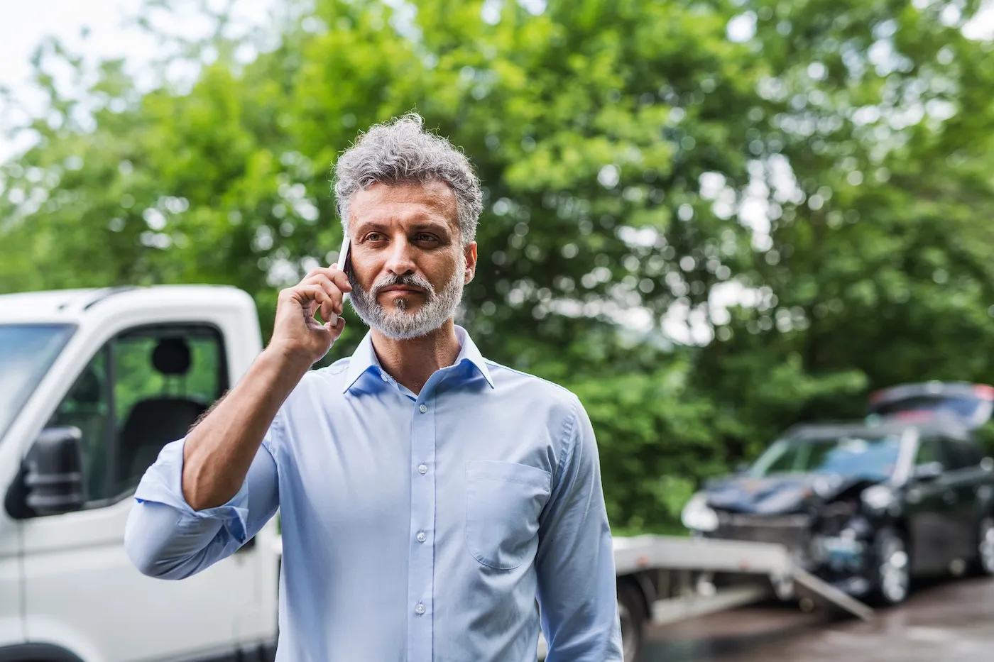 Mature man making a phone call after a car accident.