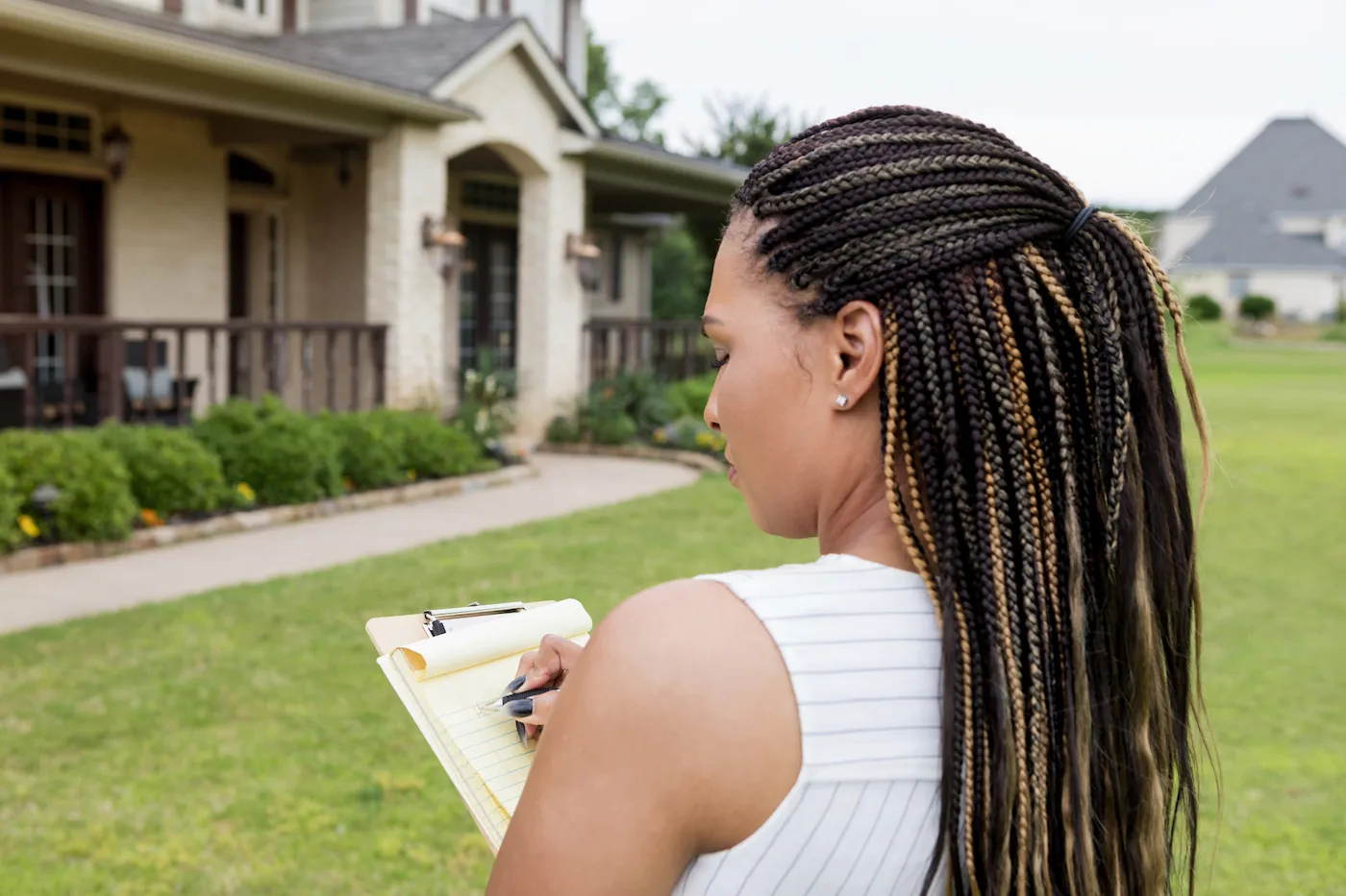 Real Estate Agent evaluates a house by writing on a notepad.