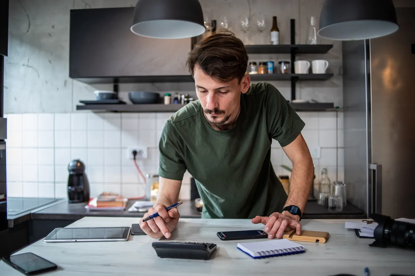 The young man uses a calculator and accounts for the condition of his financial plans at home.