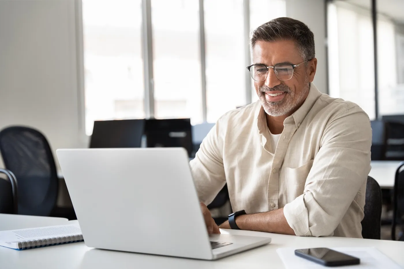 Happy smiling man using computer, typing, working in modern office.