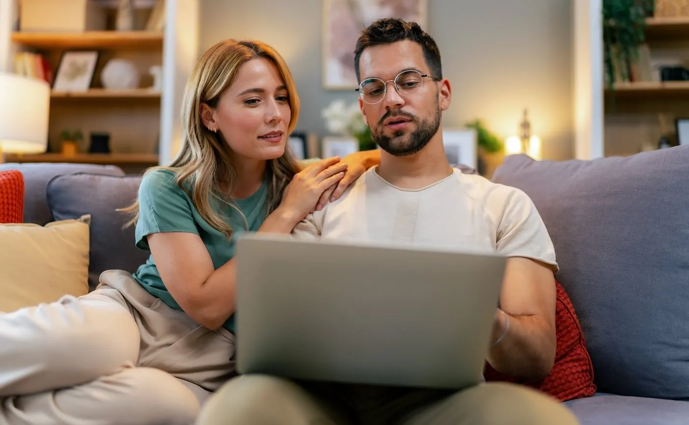 Relaxed couple sitting on a sofa with a laptop